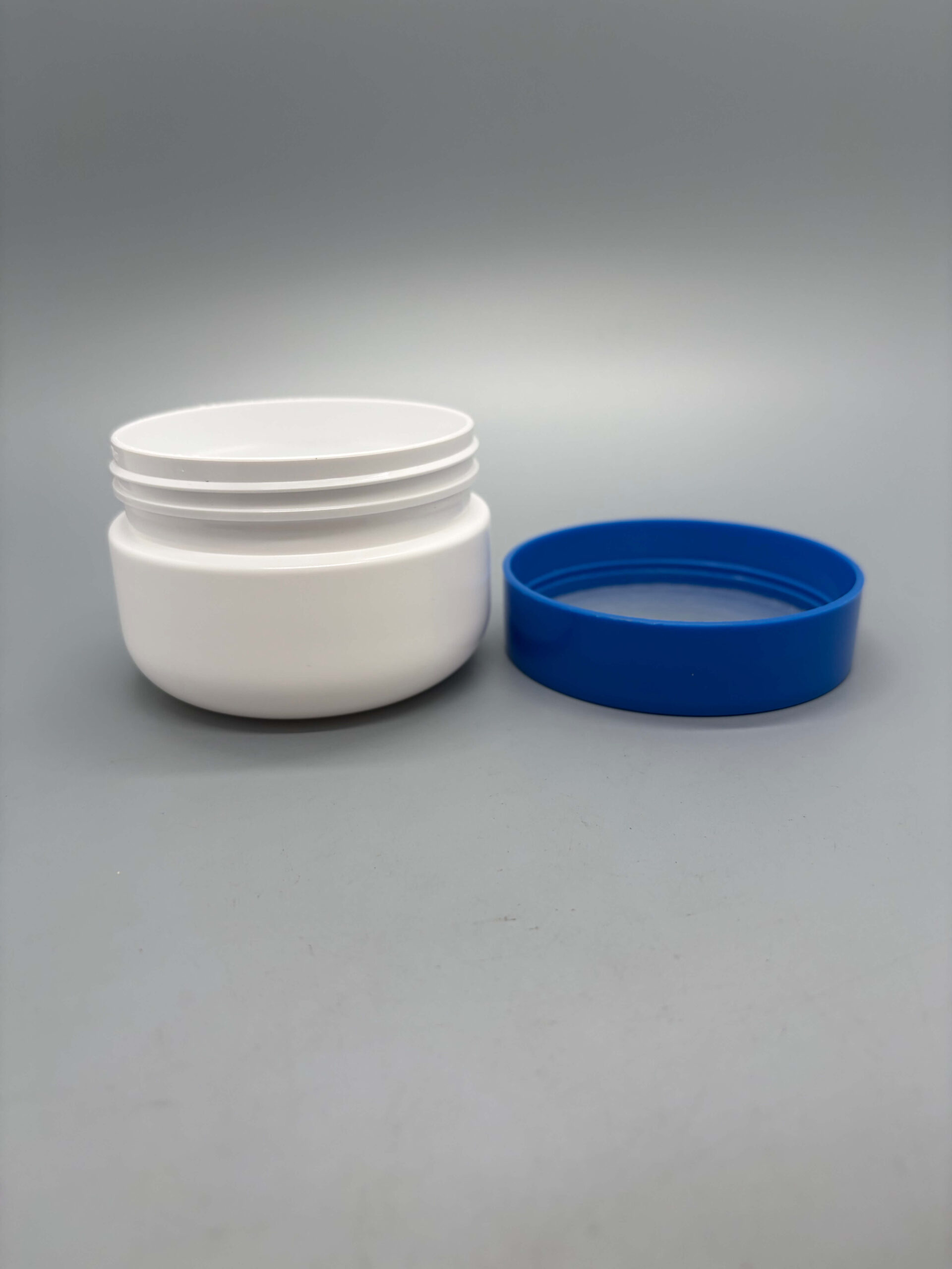 White cosmetic cream jar with blue screw lid